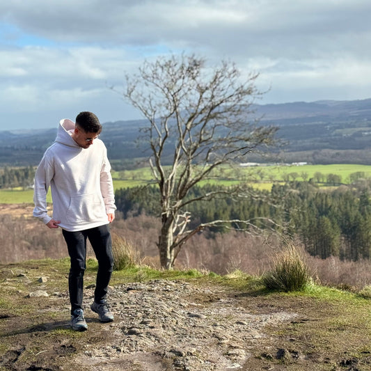 Person standing on a hill with a scenic landscape in the background