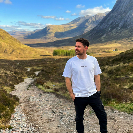 Man standing on a dirt path in a mountainous landscape