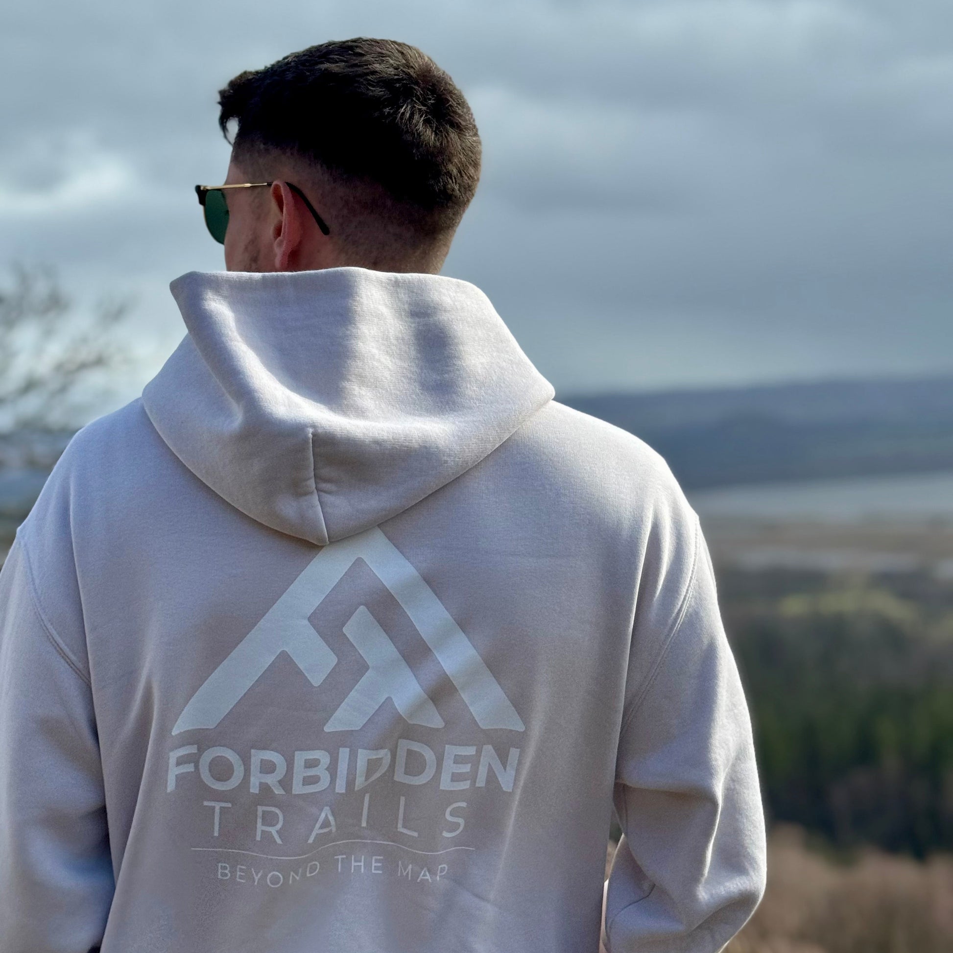 Person wearing a hoodie with 'Forbidden Trails' logo outdoors
