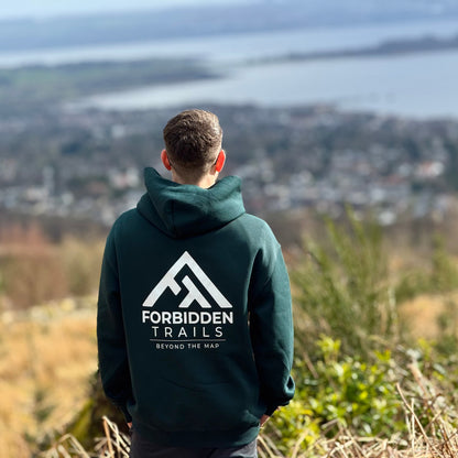Person wearing a hoodie with 'Forbidden Trails' logo overlooking a scenic landscape.