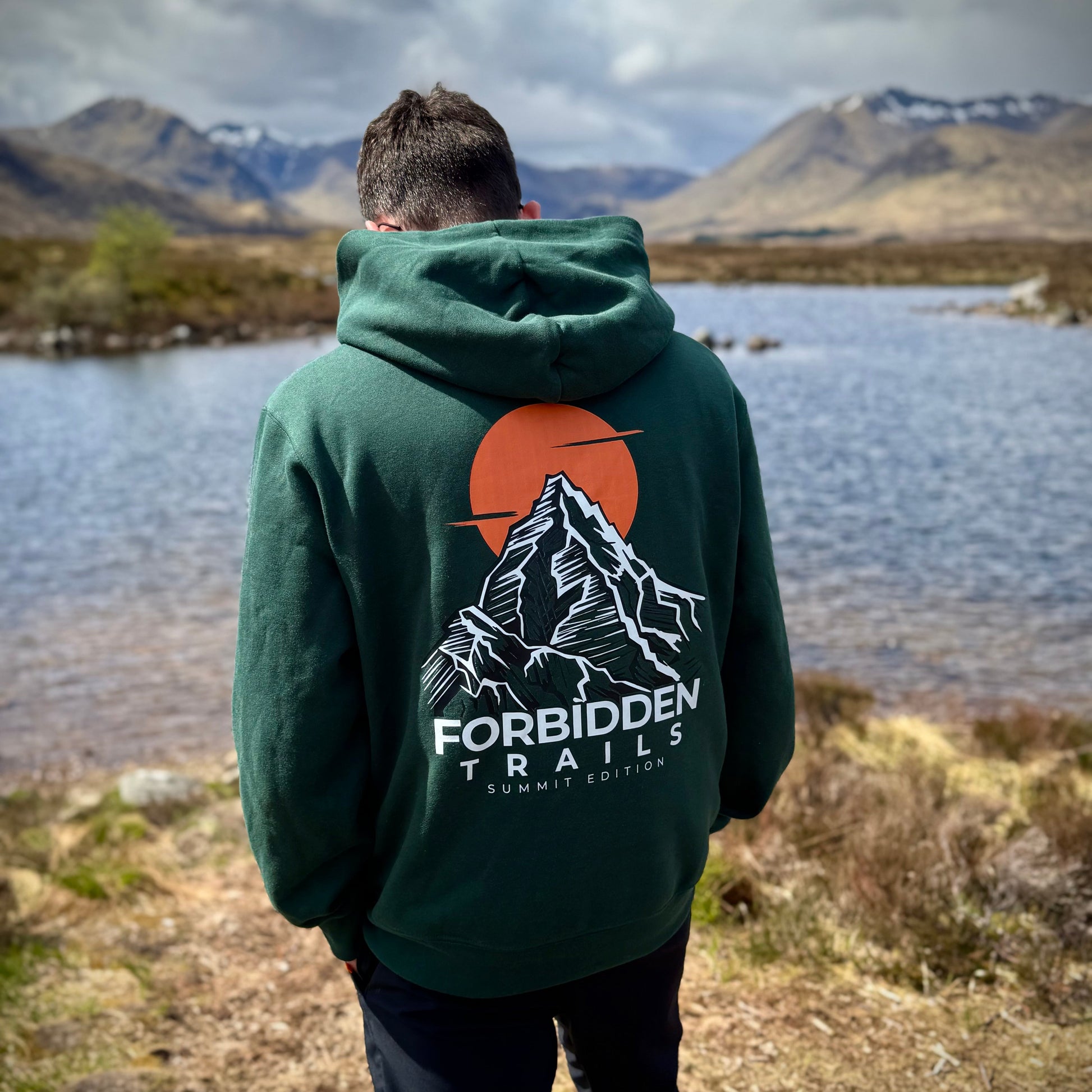 man standing with green hoodie with mountain graphic on back