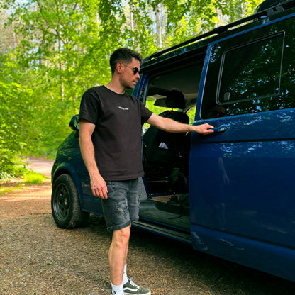 Man opening the door of a blue van in a forested area