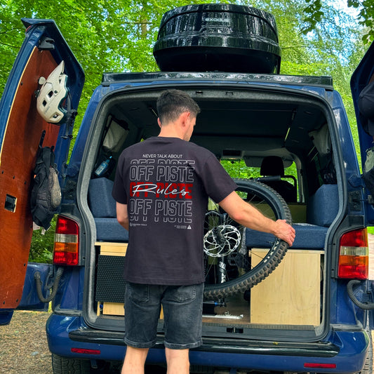 Person taking a bike out of a van wearing a black tee with  graphic on the back