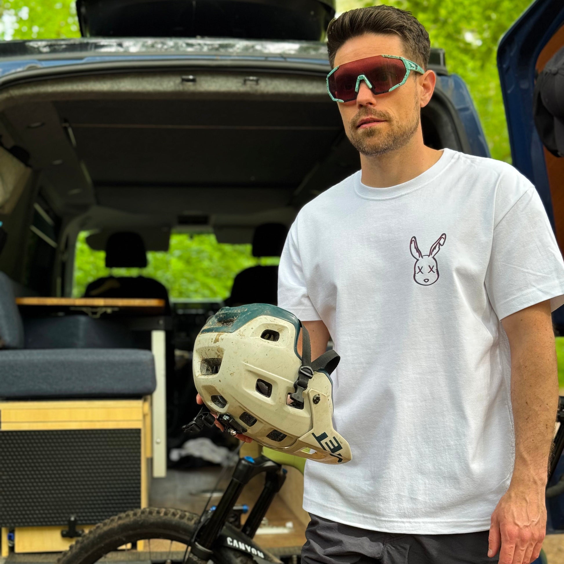 Man holding a helmet next to an open van with a bike